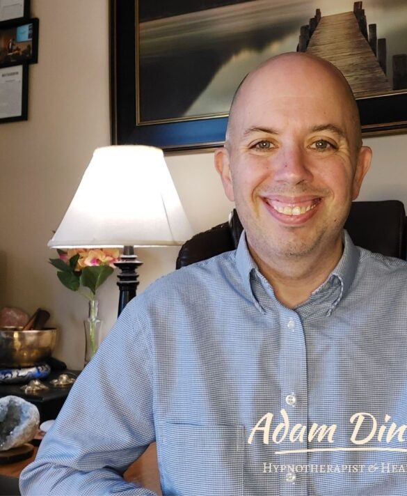 Adam Dince, hypnotherapist, smiling in his office